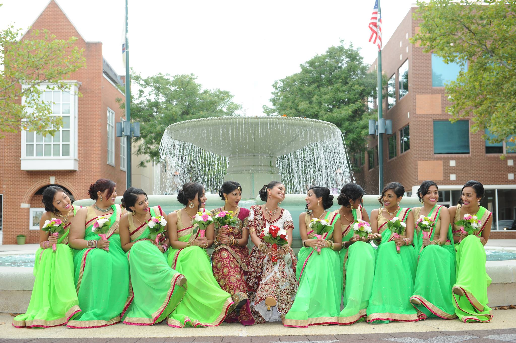 Group of women in bright green dresses posing in front of a fountain.